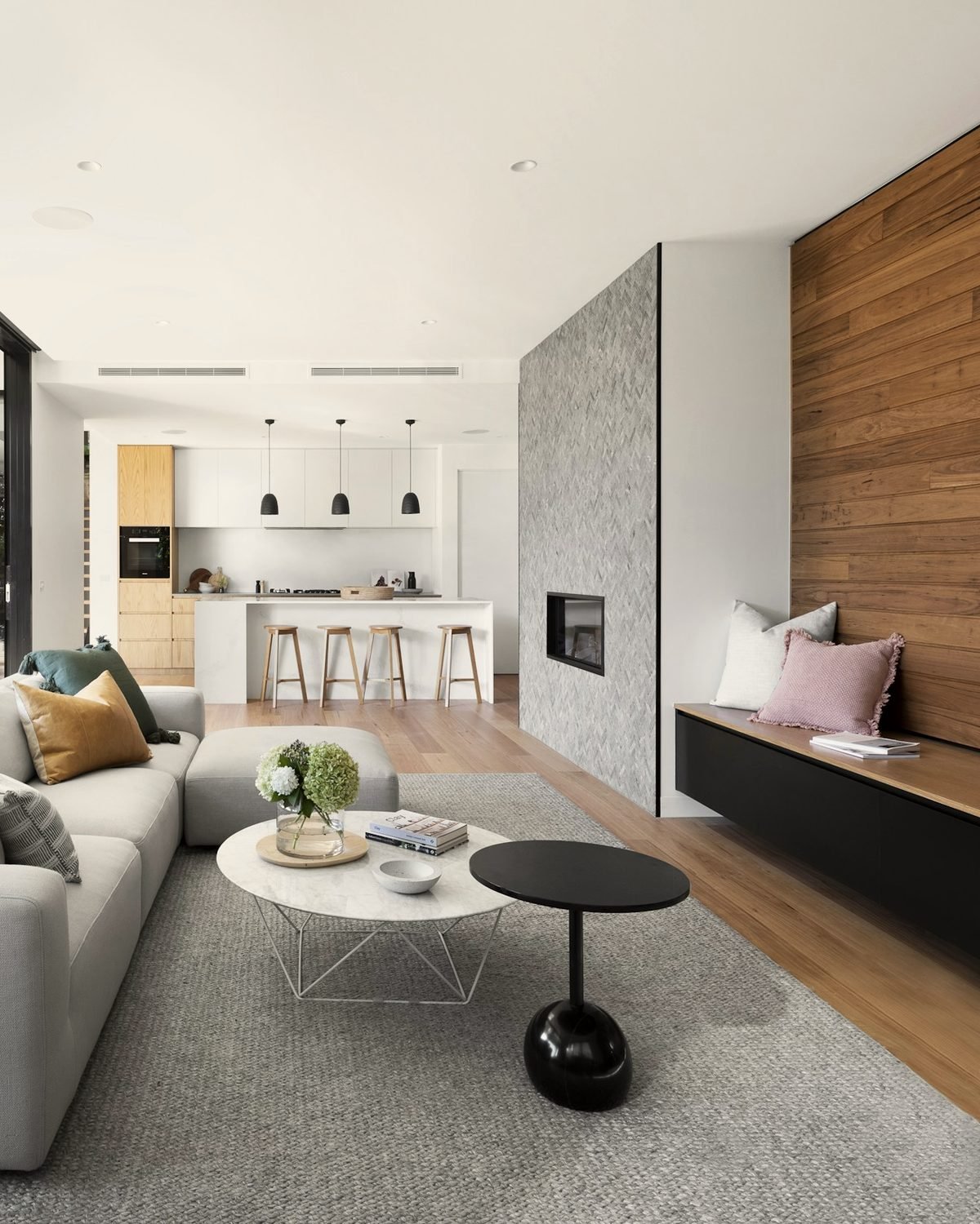 Modern interior with a warm timber wall, stone fireplace and natural light